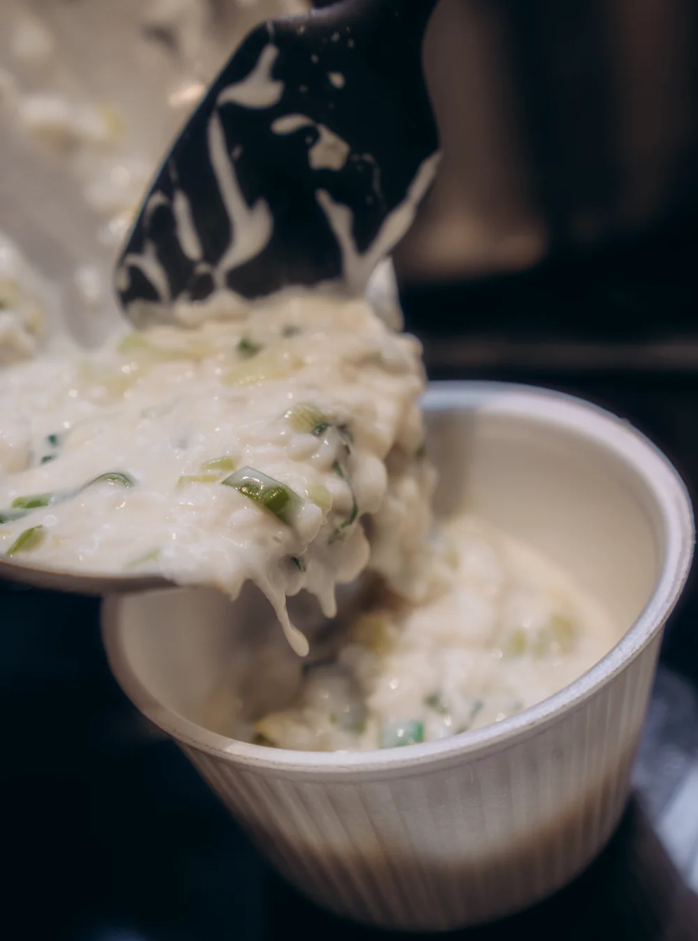 Risoto cremoso da Massita sendo servido no pote, com queijo derretido escorrendo