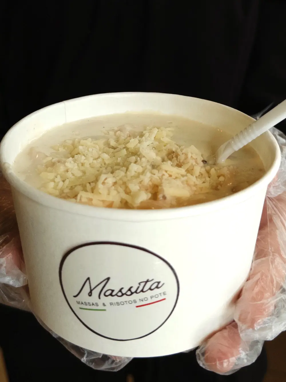 Close do pote da Massita com risoto cremoso coberto de queijo parmesão ralado na hora